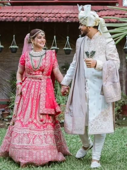 A full-length shot of our clients, showing how the bride's pink lehenga and jewellery create a cohesive and beautiful picture.