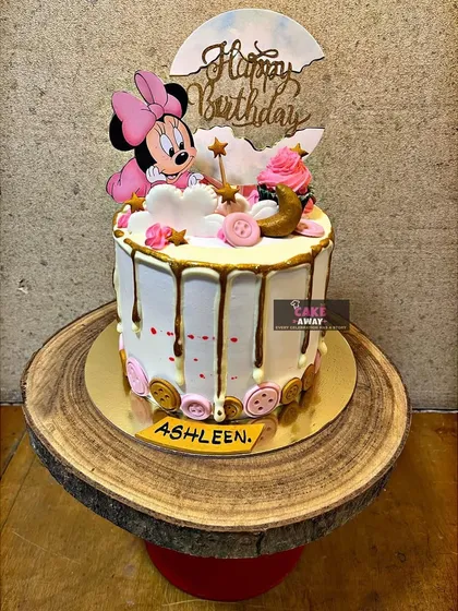 A sweet Minnie Mouse drip cake. This design includes a cute Minnie topper, a chocolate drip, and charming button details for a playful look.