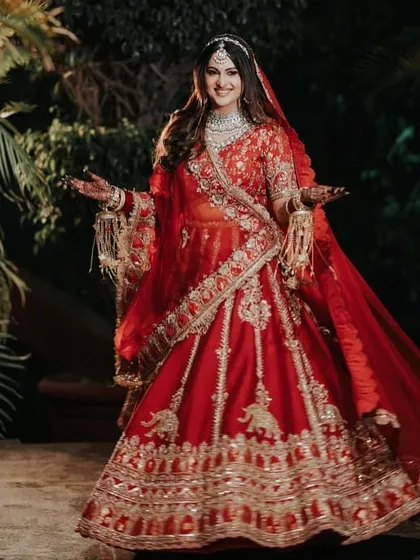 A full-length shot of the bride, capturing the magnificent flare of her red lehenga. The movement and her joyful expression make this a dynamic and beautiful portrait, showcasing her entire bridal look.