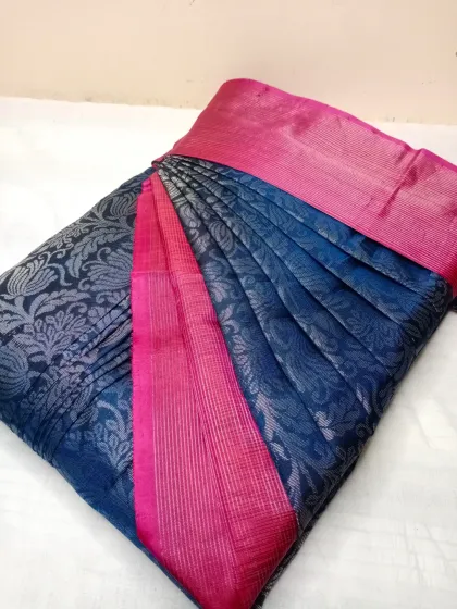 The contrast of navy blue and bright pink on this silk saree is stunning. The pleats are neatly arranged to showcase the intricate silver brocade work.