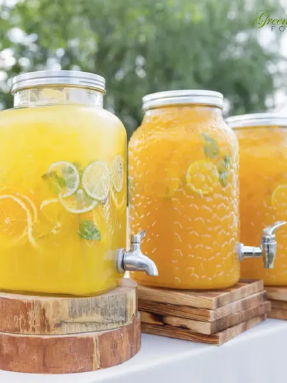 For outdoor events, refreshing drinks are a must. We set up these beautiful glass beverage dispensers filled with fresh orange and lemon-lime juice, allowing guests to help themselves to a cool drink.