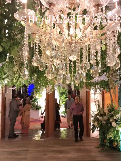 The entrance passage, with a ceiling covered in hanging greenery and a grand crystal chandelier, creating an enchanted garden feel.