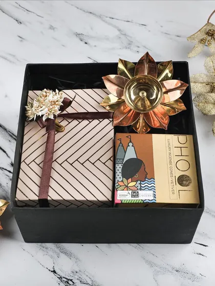 The 'Golden Lotus' hamper is a perfect combination of festive essentials. It features a beautifully wrapped gift box, a lotus diya, and Phool incense.