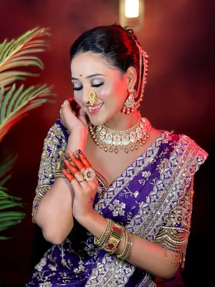 The complete bridal ensemble. This photo highlights the harmony between the makeup, hairstyle, jewelry, and the intricate purple saree.