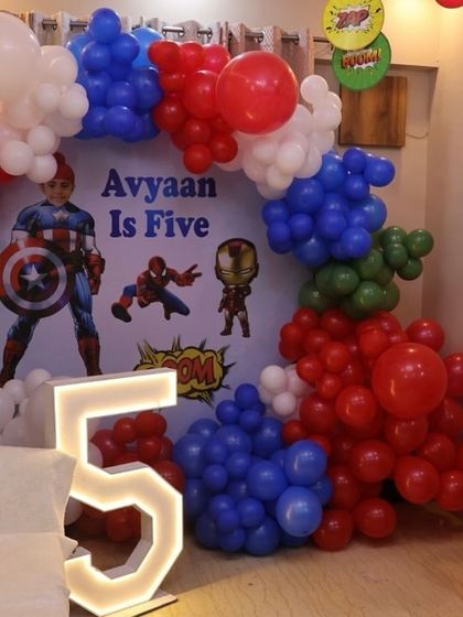 An action-packed Avenger-themed birthday setup for a five-year-old. We used the classic red, white, and blue colors of Captain America, along with a custom backdrop featuring multiple superheroes and a light-up number '5'.