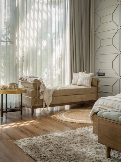 A serene bedroom corner with a comfortable daybed, perfect for reading or enjoying the view. The textured wall paneling and soft, natural light create a peaceful and relaxing atmosphere.