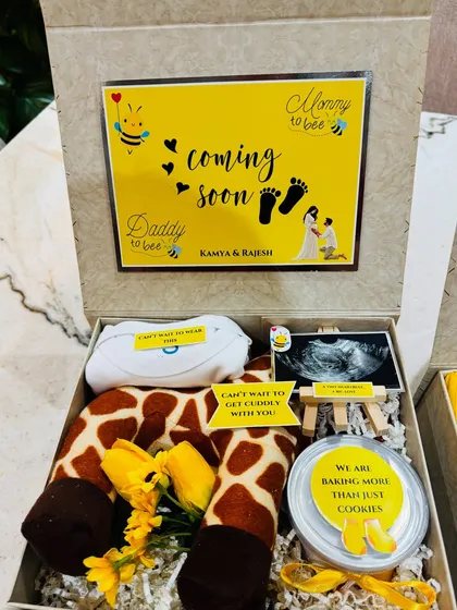 A giraffe-themed reveal box, complete with a 'Daddy to bee' announcement card, a custom onesie, and the precious sonogram photo on a miniature easel.