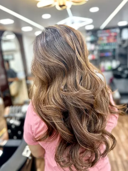 A perfect balayage from another angle, showing the seamless blend and soft waves in a salon setting.