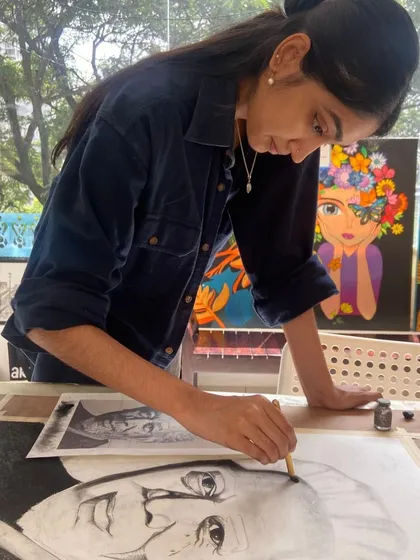 A student practices charcoal sketching, focusing on creating depth and contrast in her portrait.