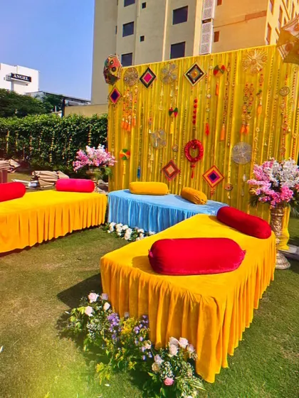 A colorful and casual seating arrangement for a Mehendi party. I used low divans with bright cushions and a vibrant backdrop with traditional hangings to create a relaxed and festive vibe.