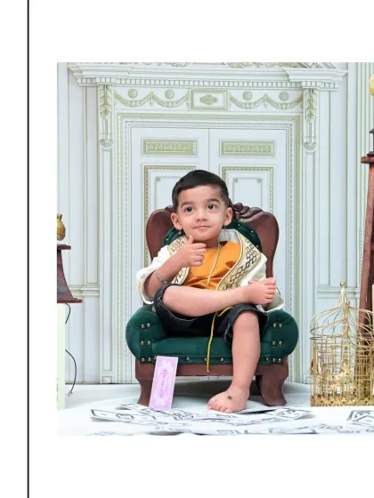 A simple, classic portrait of the toddler giving a thumbs-up. The elegant, light-colored background and his relaxed pose create a timeless and charming image.