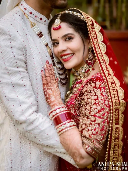A bride's happy smile as she rests her head on her groom's chest. This close-up shot focuses on her expression of comfort and joy, showcasing her intricate henna and bridal jewelry.