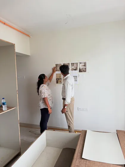 A client reviewing the design printouts taped to the wall, comparing the vision to the ongoing work.