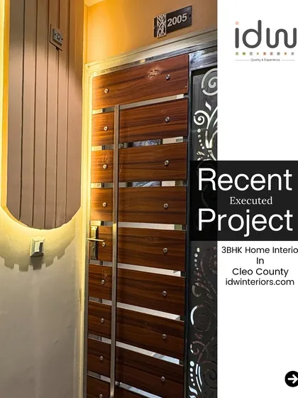 A statement main door with a modern design of wood and stainless steel panels. The backlit wall niche adds a soft, welcoming glow to the entryway.