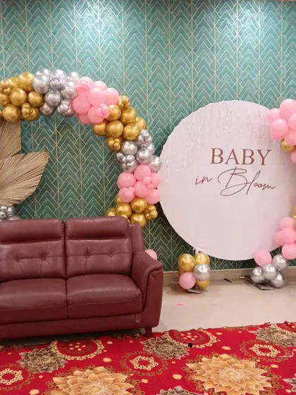 This 'Baby in Bloom' theme is perfect for a chic and modern baby shower. It features a circular backdrop for photos, framed by an asymmetrical balloon arch in pink, gold, and silver. I also incorporate natural elements like dried palm leaves to complete the look.