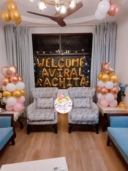 A 'Welcome Aviral Rachita' home decoration with balloon pillars and a backdrop for a newly married couple or new parents.
