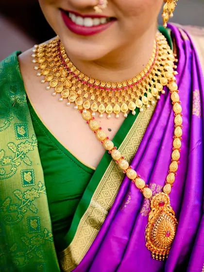 A close up on the stunning gold jewelry worn by the bride, Poorva. The intricate details of the necklace against her vibrant saree are beautiful.