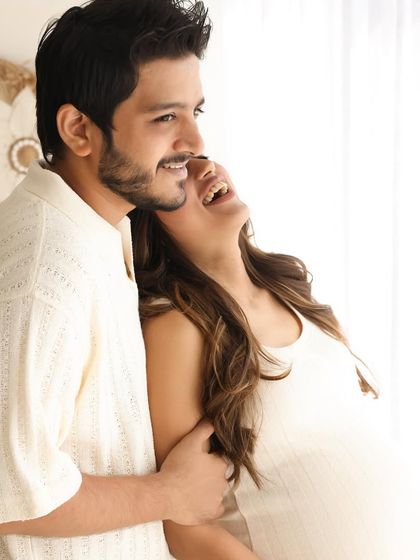 Bathed in soft window light, this candid shot captures the couple's happiness. The natural, airy feel of the studio enhances the serene and joyful mood of the portrait.