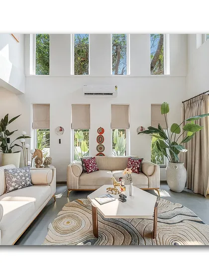 Natural light floods this double-height living room at Casa D Umravi, creating a bright and airy atmosphere. The high windows draw the eye upward, emphasizing the spaciousness, while the clean lines of the furniture and the organic patterns of the rug create a sense of modern, relaxed luxury.