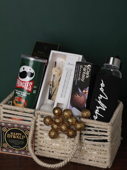 This jute-handled basket is packed with snacks and useful items. It includes Pringles, a personalized bottle, a reed diffuser, and chocolates, making it a great all-rounder gift.