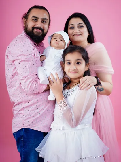 A beautiful family of four, celebrating the arrival of their newest member. The older sister gently holds her baby brother, creating a heartwarming family portrait.
