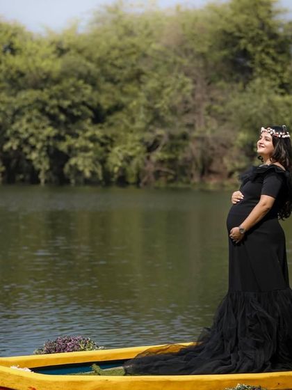 Our black off-the-shoulder mermaid gown is a client favorite. It offers a timeless, elegant look that beautifully accentuates the baby bump, perfect for both studio and outdoor settings.