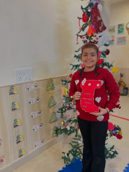 An older girl proudly shows off her completed red Christmas stocking.