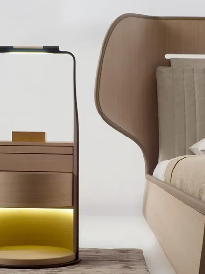 The revolving bedside unit shown next to a bed, illustrating its practical elegance and how it provides storage, display, and lighting in one compact, beautifully designed piece.