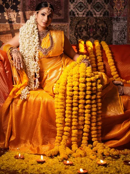 A full-length shot of Tanishaa Mukerji seated like a queen, surrounded by marigold flowers and diyas. This image captures the complete grandeur and sacred ambiance of the theme.