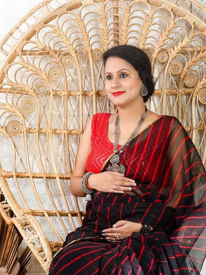 A modern take on traditional wear. This mom-to-be looks stunning in a black and red striped saree, seated in our popular peacock chair.