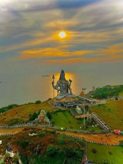 A beautiful sunset view of the giant Shiva statue at Murudeshwar, with the Arabian Sea in the background.