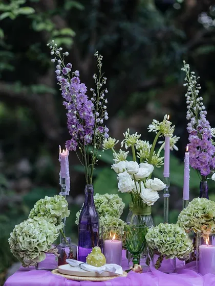 A close-up of the elegant floral centerpiece, with tall purple delphiniums and white ranunculus.