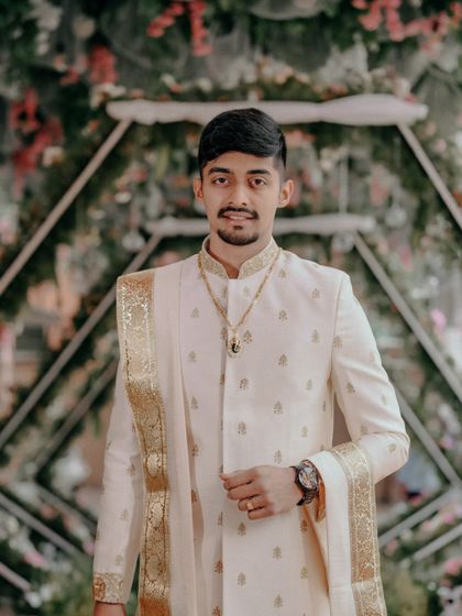 A handsome groom in his traditional Muhurtham attire, posing against a floral backdrop.