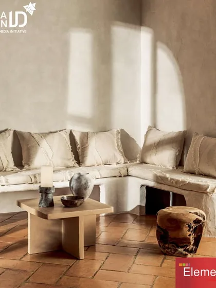 An L-shaped sectional sofa built into a rustic, plaster-finished niche. The neutral, textured upholstery and frayed-edge cushions create a look of relaxed, earthy sophistication, showcasing our ability to create custom seating for unique architectural spaces.