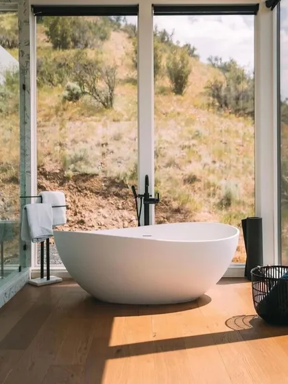 A luxurious freestanding bathtub is positioned to take full advantage of the scenic views. This bathroom design turns a daily routine into a spa-like experience.