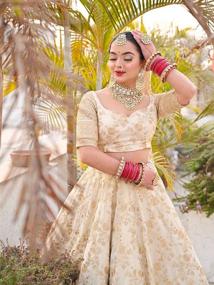 A candid pose showing the contrast of the red choora against the subtle ivory lehenga.