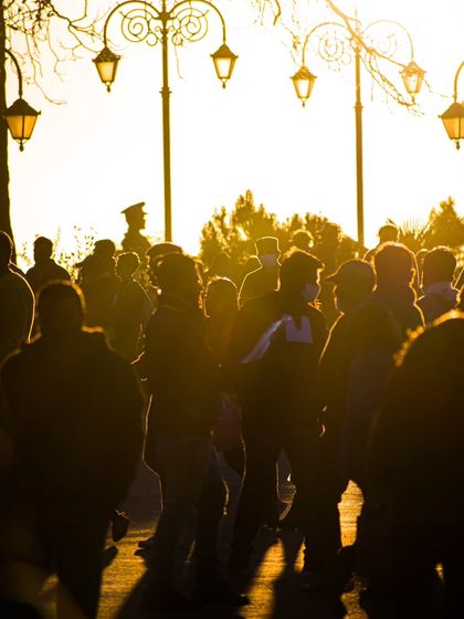 A crowd of people silhouetted against the setting sun in Shimla, creating a warm, atmospheric street scene.