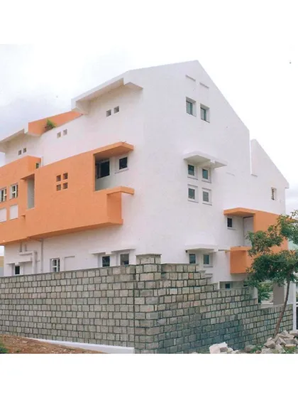 A view of 'Nachiar Illam' showcasing its multi-faceted facade. The orange panels are not just decorative but define different functional zones within the split-level home.