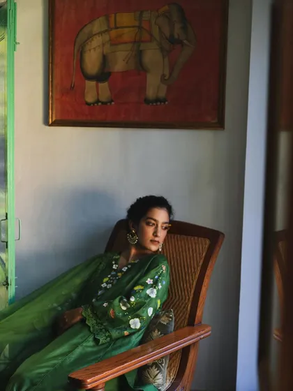 A wider shot from the same series for Baavli, showing the model in a relaxed pose against a backdrop of traditional Indian art.