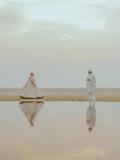 An artistic and serene portrait of a couple on the beach, their figures perfectly reflected in the calm water, showcasing our creative approach to couple photography.