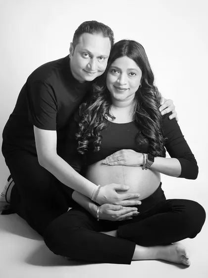 A happy black and white couple's portrait. They are seated in a casual pose, both looking at the camera with warm smiles, creating a friendly and approachable feel.