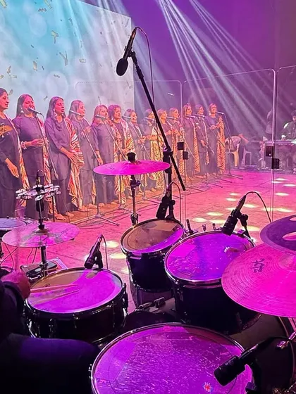 The view from behind the drum kit as our adult choir performs under the vibrant stage lights.