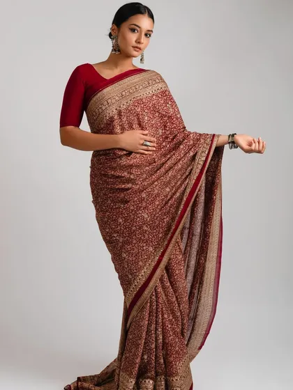 A full view of the royal red saree look. The makeup and hair are kept clean and sharp to let the intricate saree and the model's powerful presence stand out.