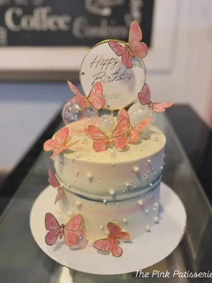 A dreamy butterfly cake with a watercolor finish, clear bubble decorations, and a "Happy Birthday" topper.