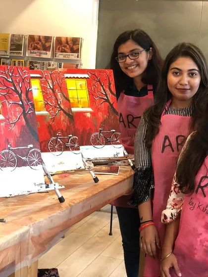 Three participants with their festive red Christmas paintings. The holiday themed workshops are always a hit.