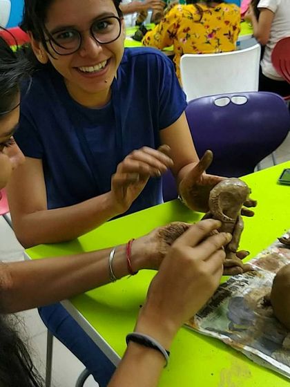 The joy of collaboration! Two participants work together on a Ganesha sculpture during a corporate workshop, sharing smiles and creative energy.