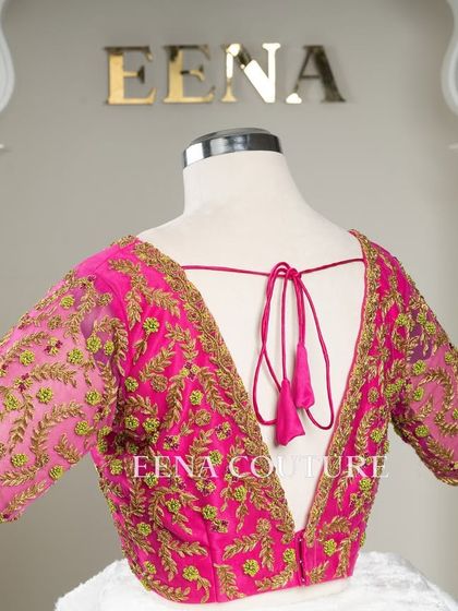 Grace in every detail. This pink net blouse features delicate leafy vines embroidered in gold and light green thread. The deep V-back and sheer sleeves add a touch of modern femininity.