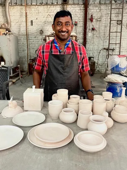 A proud moment! This student is showing off a fantastic collection of bowls, plates, and pots, all perfectly formed and ready for the next step of glazing.