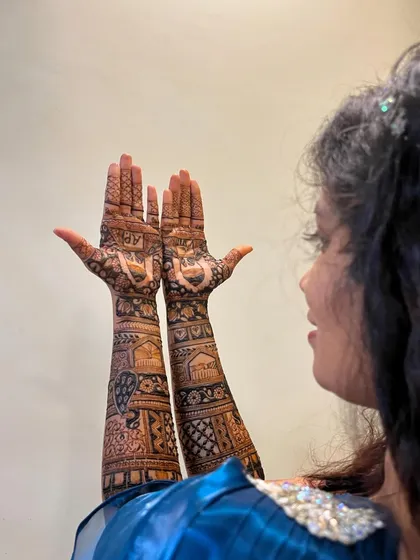 An over-the-shoulder shot of the bride, giving a unique view of her stunning back-hand mehendi.
