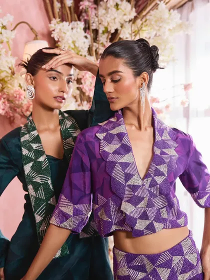 A close-up shot highlighting the interaction between two models and their complementary makeup. The look features a subtle shimmer on the eyes and a soft pink lip, perfect for festive occasions.